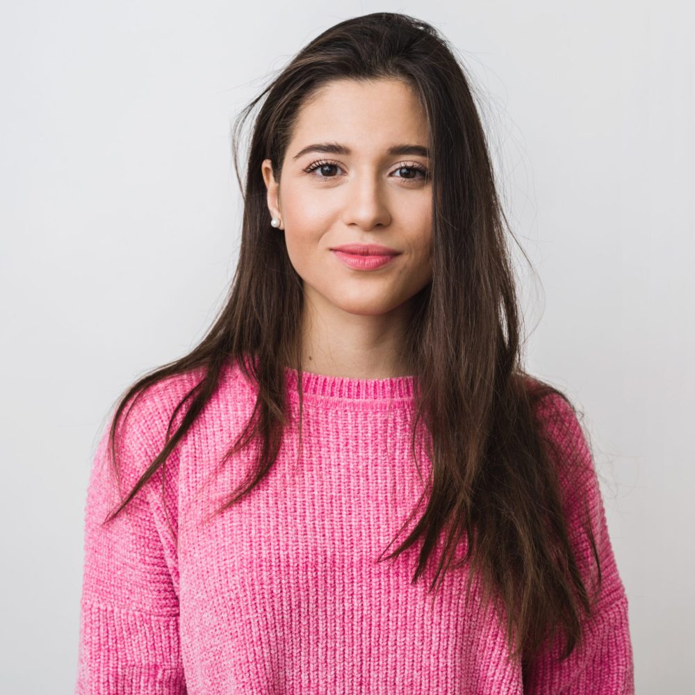 young and beautiful woman in pink warm sweater, natural look, smiling, portrait on white studio background, isolated, long hair